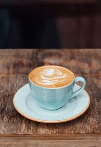kop koffie met een jkaverblad in het schuim getekend