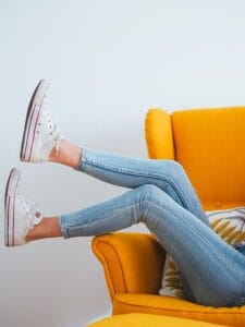Vrouw achterover op fauteuil met een spijkerbroek
